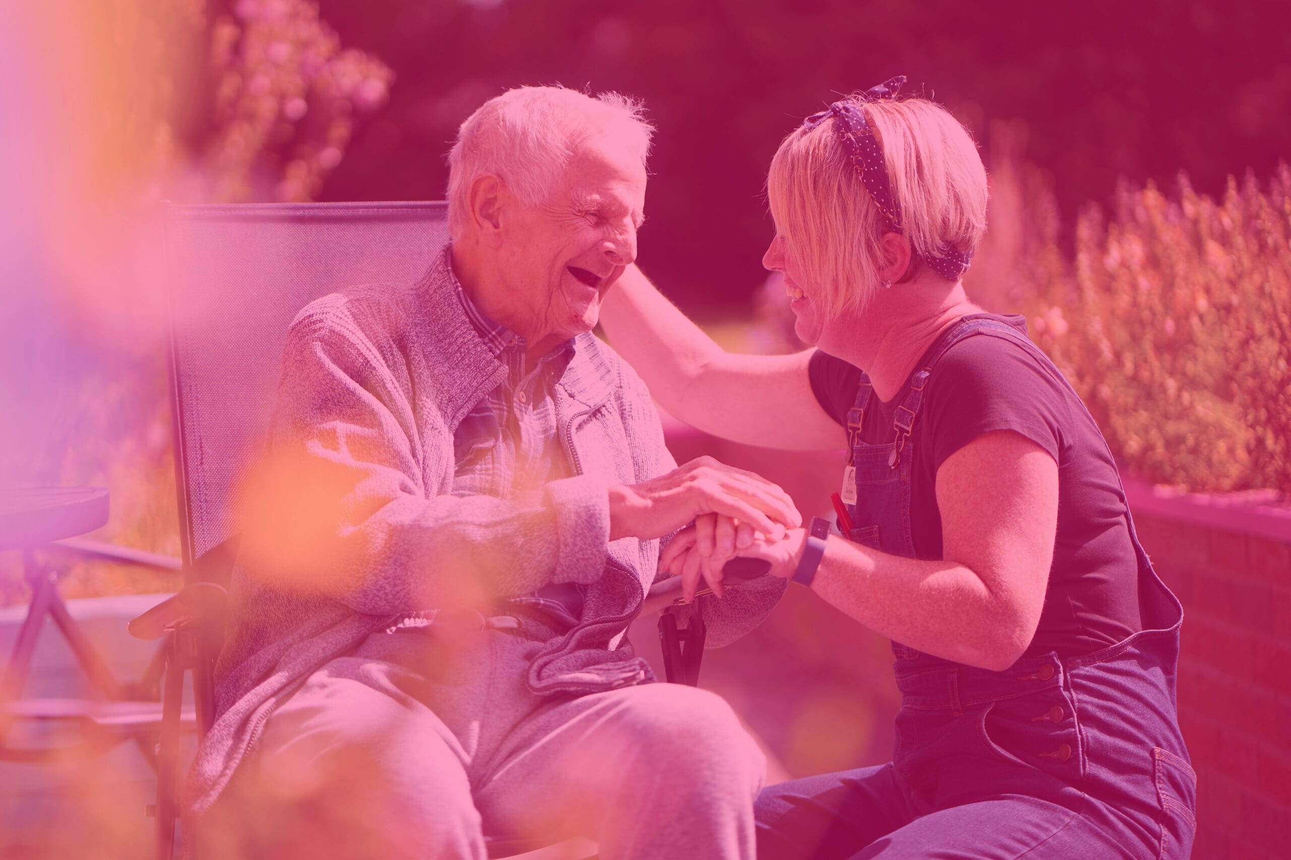 pink tinted image of elderly man with young carer