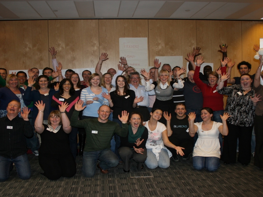 group of business professionals pulling fun faces and waving at the camera